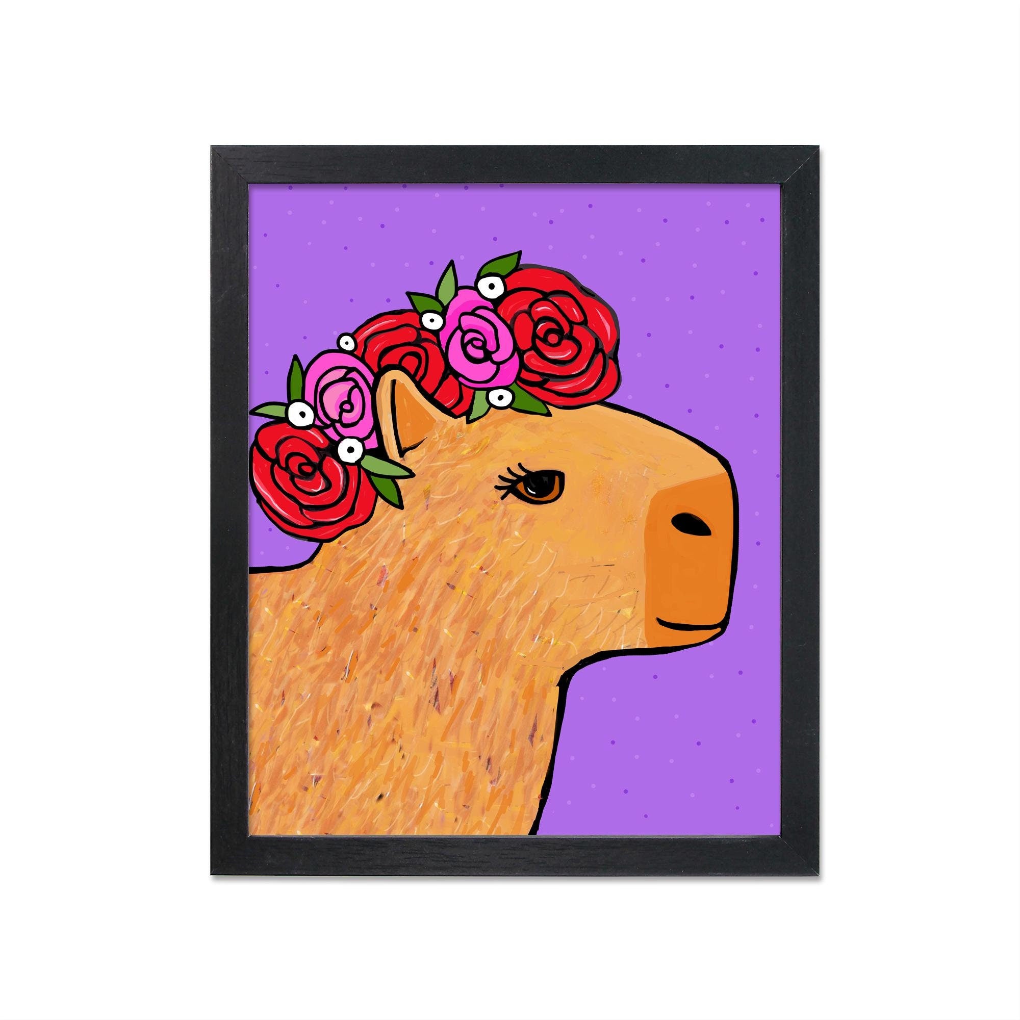 Capybara in Rose Crown art print shown in black frame. Art features a side view of a brown capybara with eyelashes with a rose crown with red and pink petals and green leaves.
