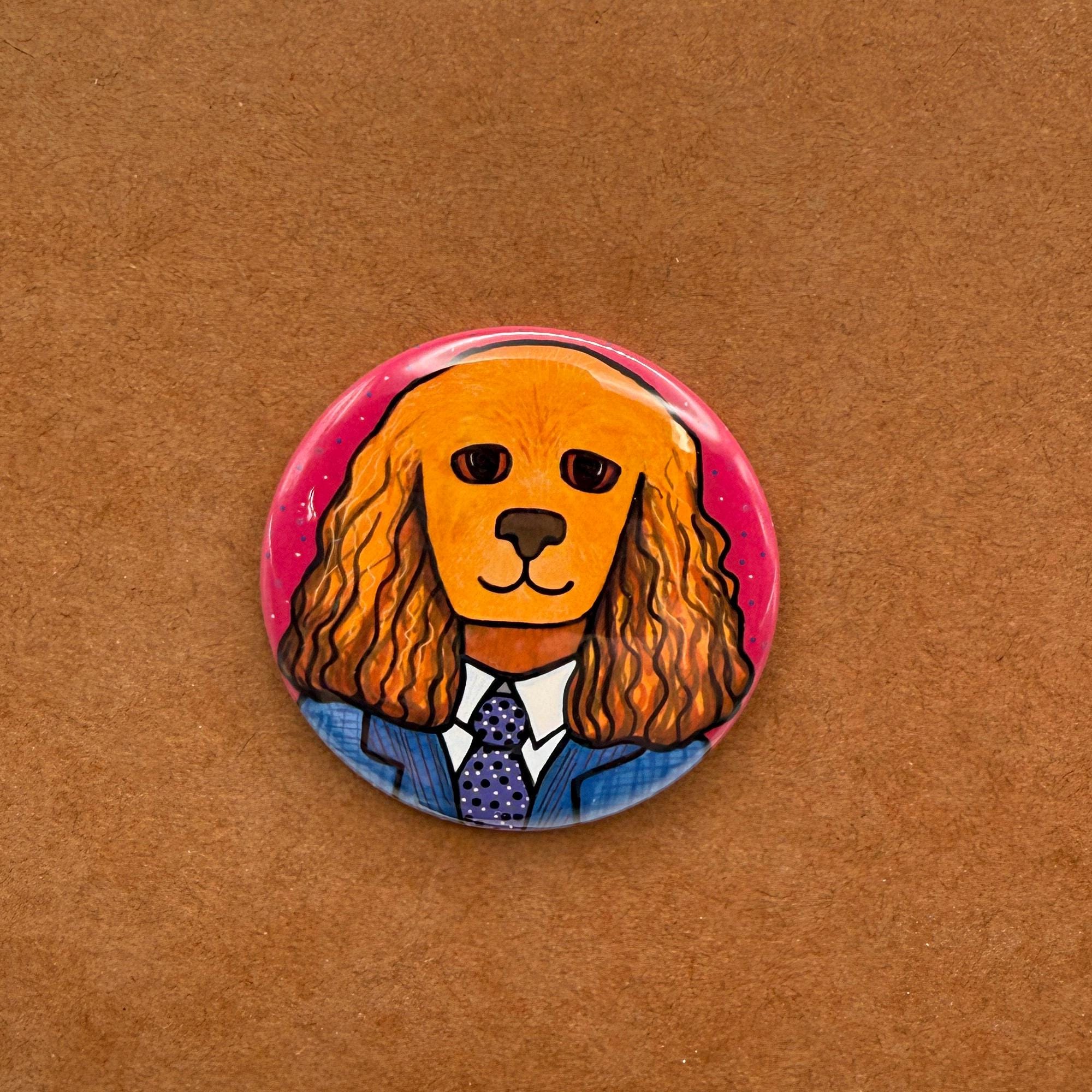 round button with Tanner the Cocker Spaniel in a blue suit with purple tie on a pink background