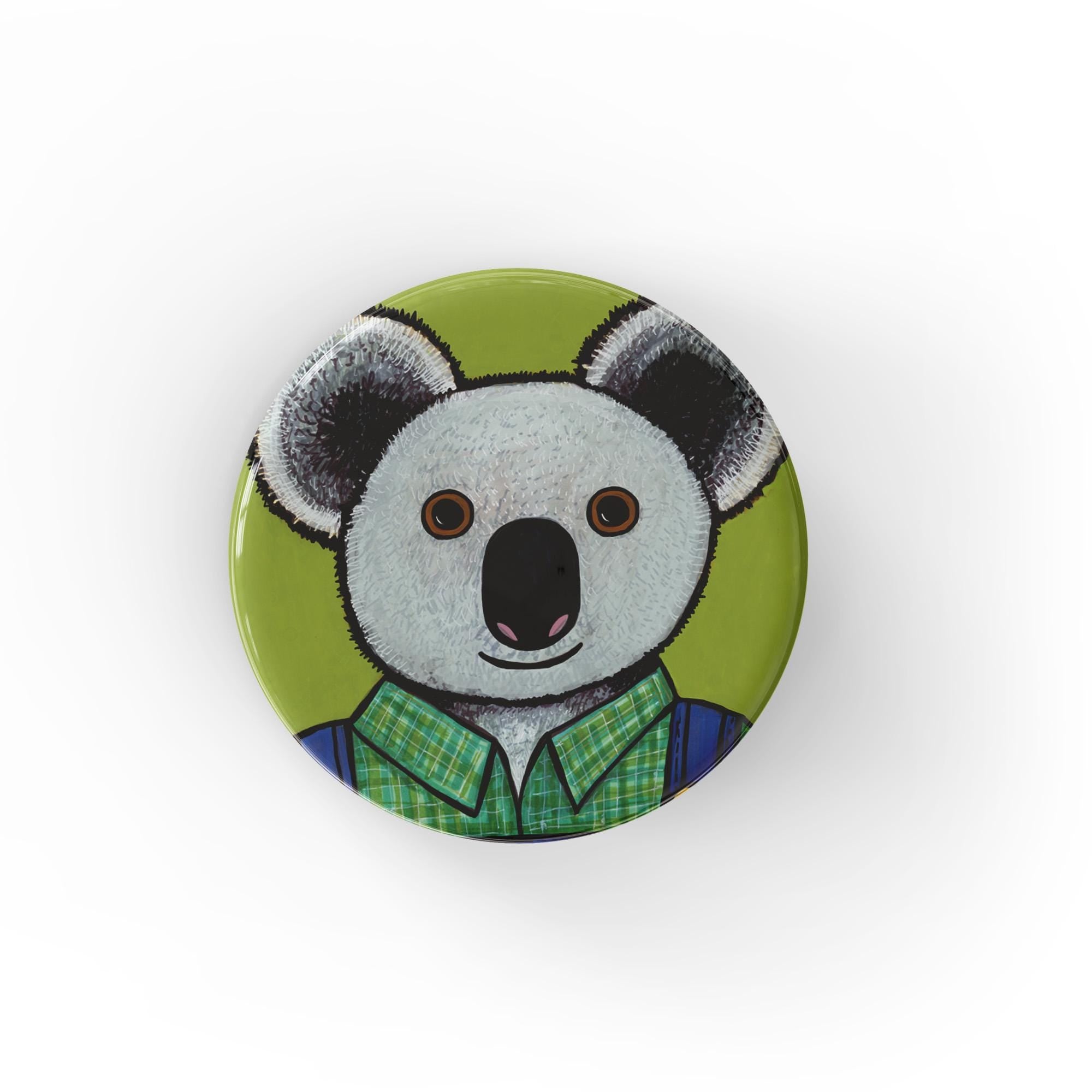 Round koala bear pin or magnet featuring Oliver the Koala in green plaid shirt and blue overalls on a bright green background.