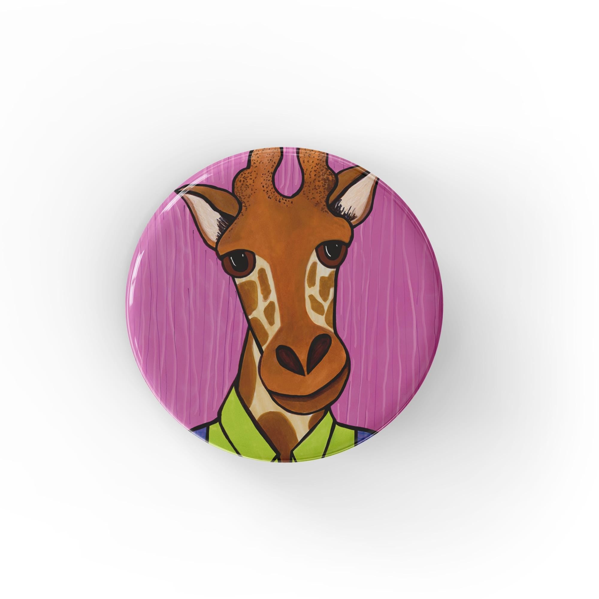 Round giraffe pin or magnet on a white background. Giraffe is wearing a bright green shirt and blue overalls and the background of the design is pink with vertical stripes.
