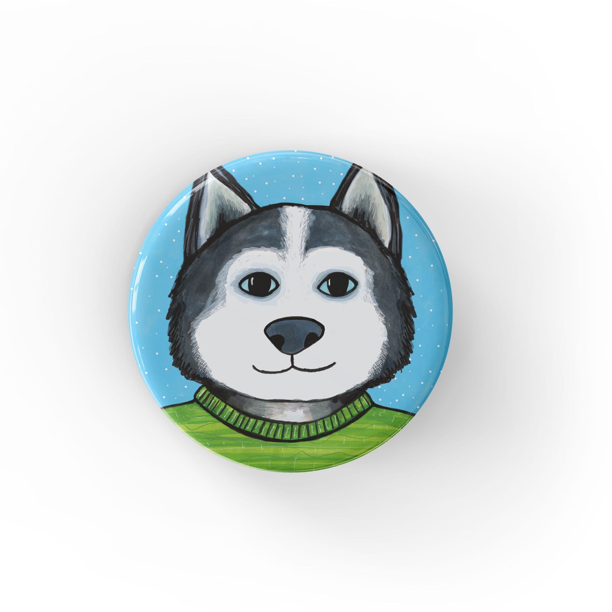 Round siberian husky pinback button or fridge magnet shown on a white background. The pin features a siberian husky in a light green sweater on a light blue background with snow flurries.