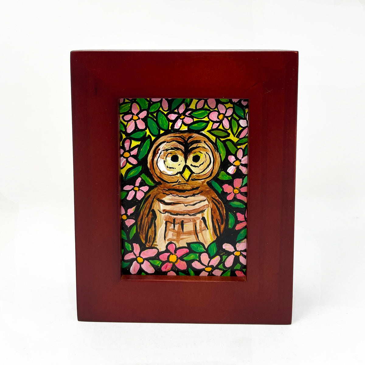 Front view of Barred Owl painting by Claudine Intner. Barred owl surrounded by pink apple blossoms and green leaves in cherry wood frame.