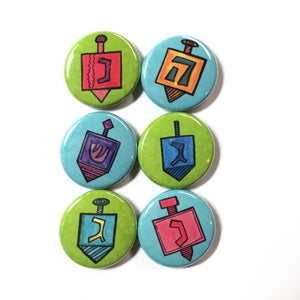 set of 6 round buttons. 3 have green backgrounds and 3 have blue backgrounds. Each one has a different dreidel.