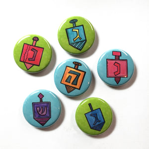 set of 6 round buttons. 3 have green backgrounds and 3 have blue backgrounds. Each one has a different dreidel.