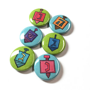 set of 6 round buttons. 3 have green backgrounds and 3 have blue backgrounds. Each one has a different dreidel.