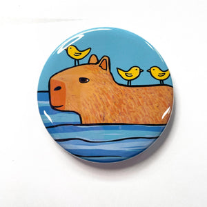 Capybara swimming in water with three yellow birds on his back