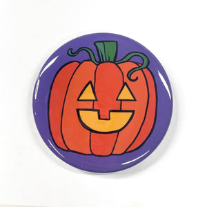 Halloween Jack O&#39;Lantern pin or magnet. Orange pumpkin with yellow happy face on purple background.