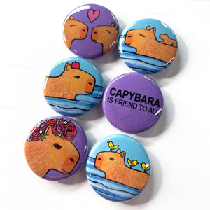 Capybara magnet or pin set - 6 designs including capybara is friend to all on purple, capybara with apple on head in the water, capybaras in love with heart, baby capybara riding on his swimming mom, capybara with rose crown, and capybara with birds