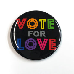 round black button with the words Vote for Love in all caps and rainbow colors. Each letter is a different color.