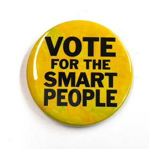 Round yellow button with the words Vote for the Smart People in a black sans serif font. Yellow background has shades of yellow.