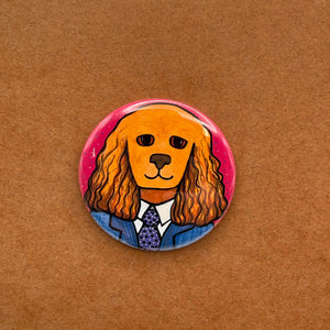 round button with Tanner the Cocker Spaniel in a blue suit with purple tie on a pink background