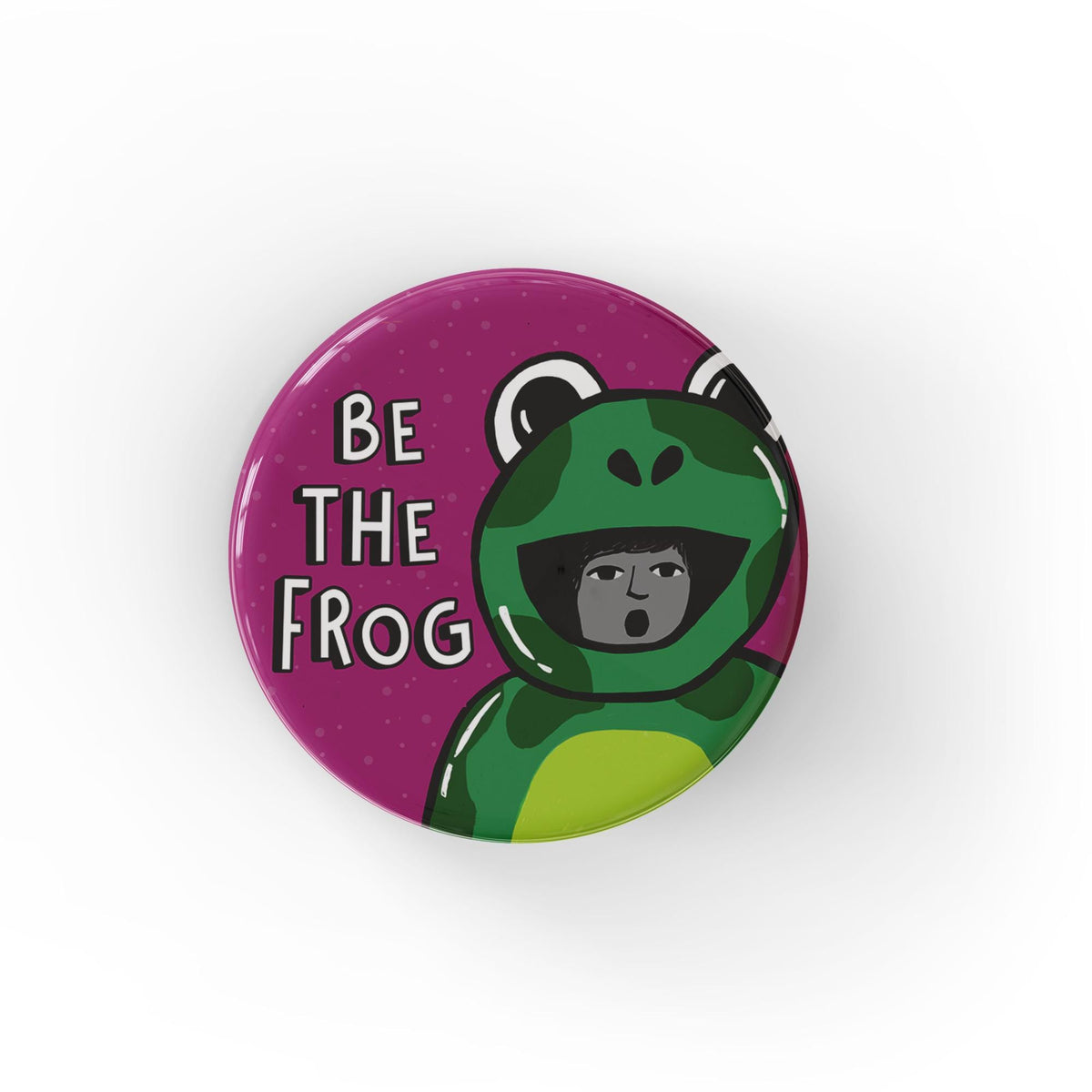 round button with the words Be The Frog in white on a deep magenta background with a person in a frog costume like the Portland Frog