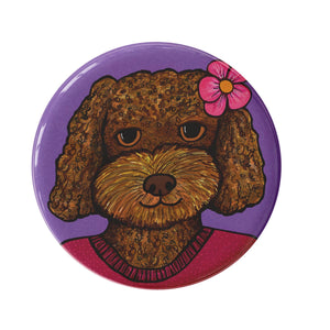 round button with a brown golden doodle dog with a pink flower in her hair and cranberry sweater on a purple background