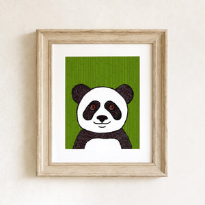 Panda art print in a wood frame with white matte on white wall. The print features a black and white panda with brown eyes on a green bamboo background.