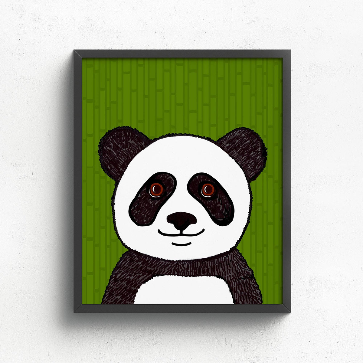 Panda art print in a black frame on white wall. The print features a black and white panda with brown eyes on a green bamboo background.
