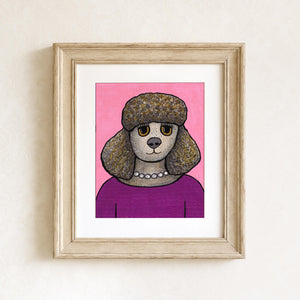Penelope the Poodle print shown in a light brown wood frame and white matte on a white wall