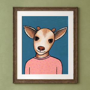 Goldie Goat art print shown in a brown frame and white mat on a green wall