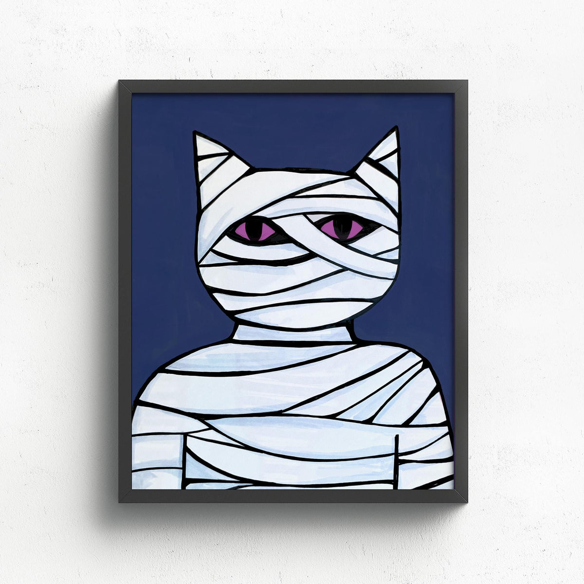8x10 inch art print featuring Cat Mummy - wrapped in white bandages with piercing purple eyes on dark blue background. Shown in a black frame.
