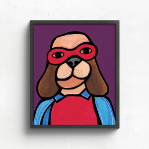 Dog in Super Hero Costume Art Print shown in black frame on white wall. The brown hound dog is wearing a red mask and body suit and a blue cape. He is set against a purple background.