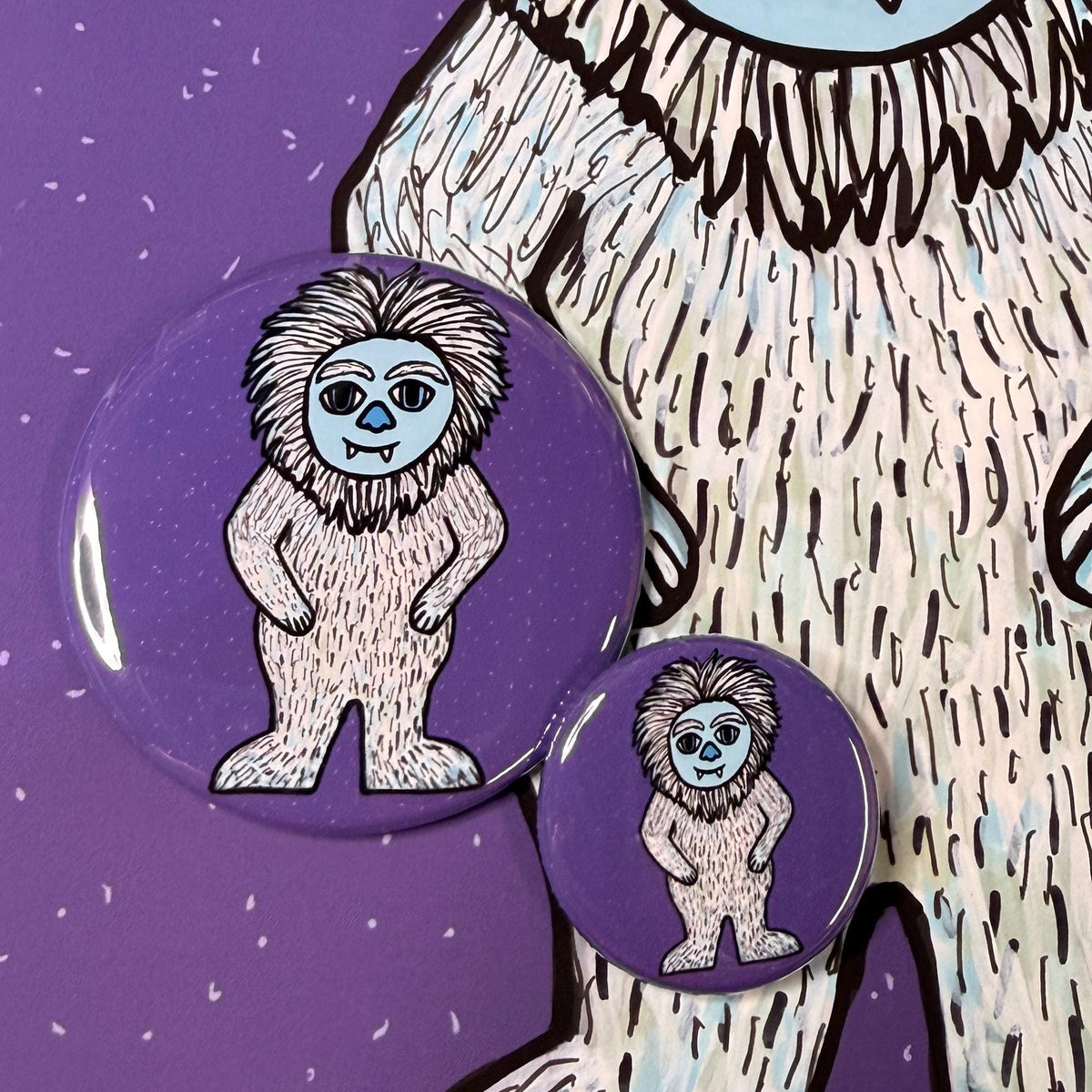comparison view of 2.25 inch and 1.25 inch yeti buttons shown on detail of yeti art print