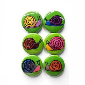 colorful round snail button set of 6 includes purple and yellow snail, purple and blue snail, brown and red snail, pink and yellow snail, blue and pink snail, and orange and gray snail - all on green backgrounds