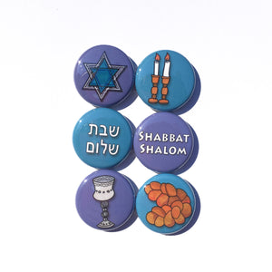 Round button set with 6 different designs. 3 blue ones with candlesticks, shabbat shalom in hebrew, and challah loaves. 3 purple ones with star of david, shabbat shalom, and kiddush cup. 