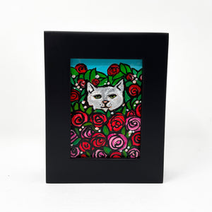 Rose Kitty II painting - front view. Painting features gray and white cat in a rose bush surrounded by pink and red roses and green leaves. Blue sky peeks out of the top of the scene.