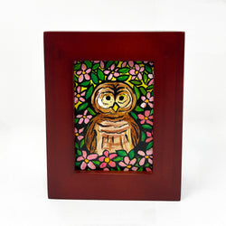 Front view of Barred Owl painting by Claudine Intner. Barred owl surrounded by pink apple blossoms and green leaves in cherry wood frame.