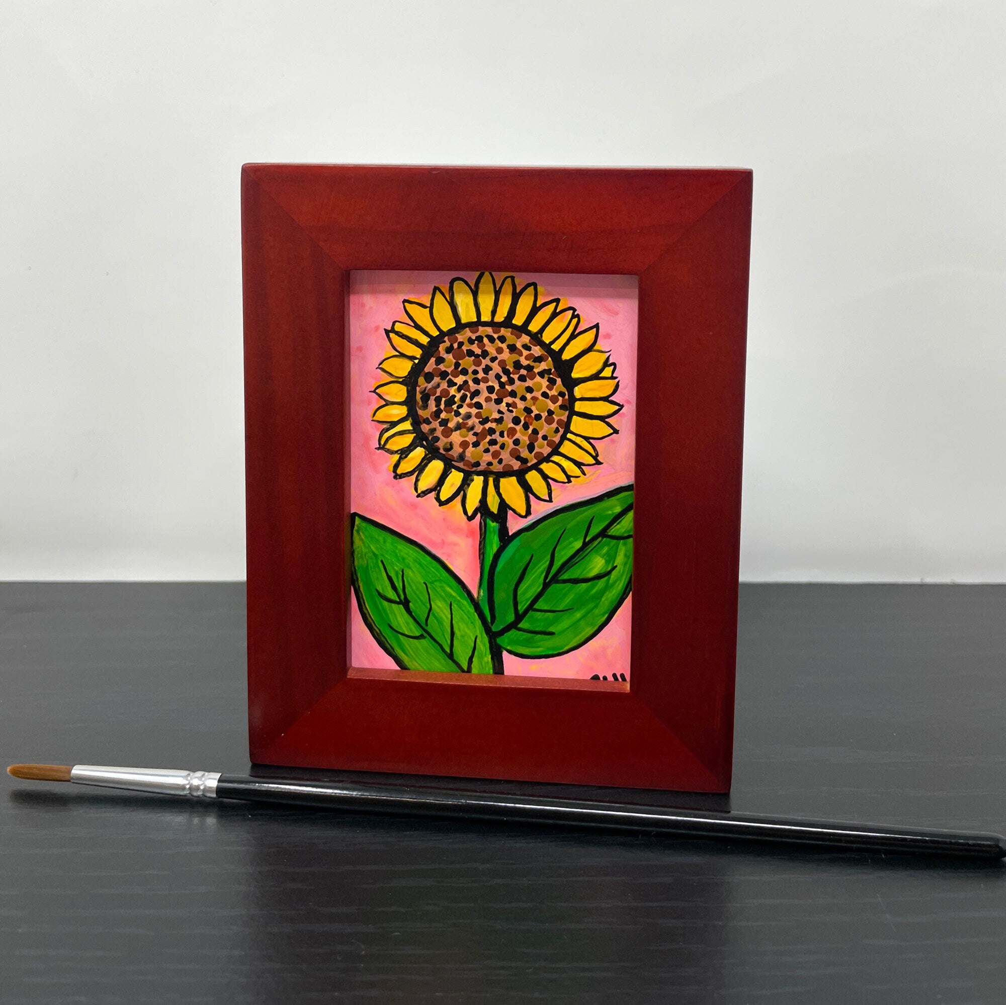 View of sunflower painting in frame with paint brush