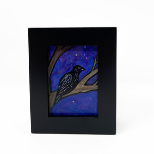 Raven painting in black frame - Black raven sits on tree branch with purplish blue sky in with stars in the background